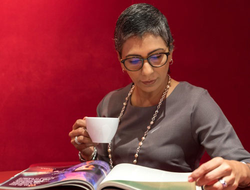 Middle aged woman drinking coffee and reading magazine